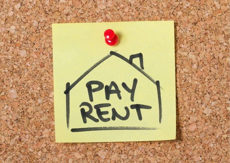 Cork board with sign saying pay rent