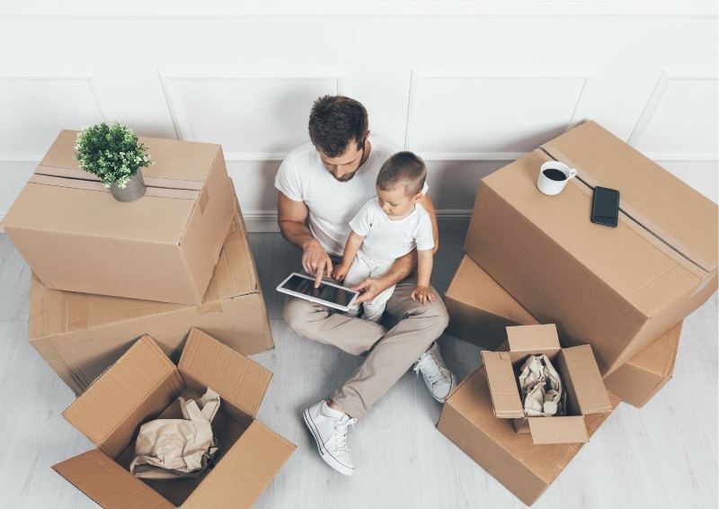 Man with Child looking a tablet while packing up their home