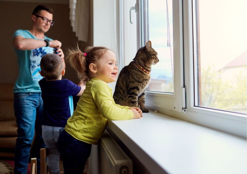 Family with cat looking out a window