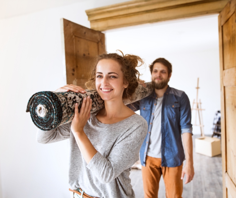 Couple carrying a rug for the new home