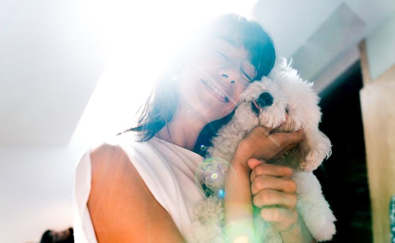 lady cuddling a dog in the sunshine