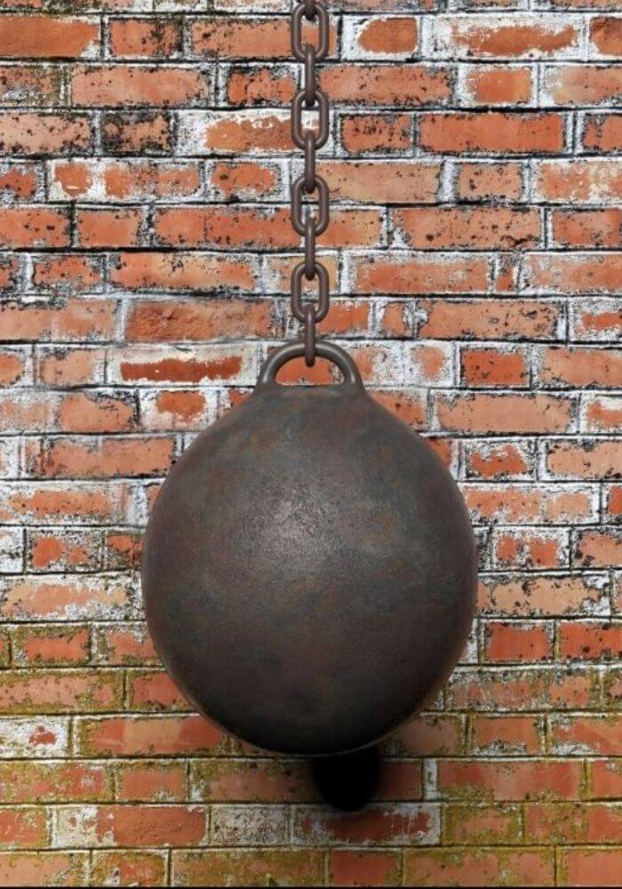 demolition ball hanging in front of brick wall